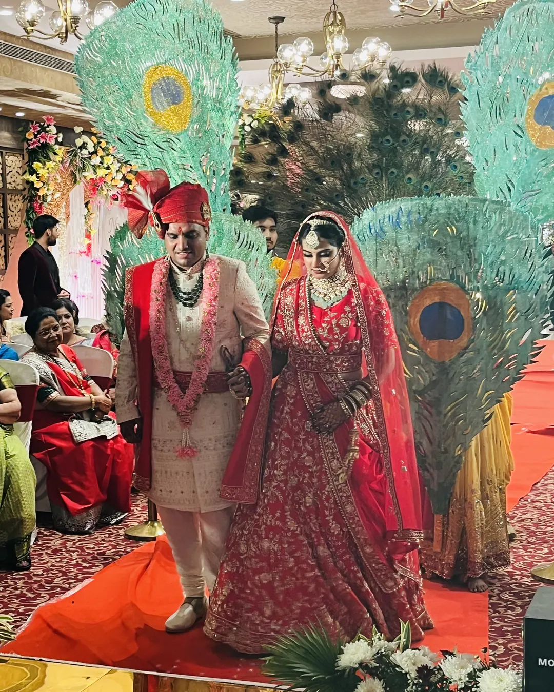 Bride and groom entering past giant peacock-feather installations
