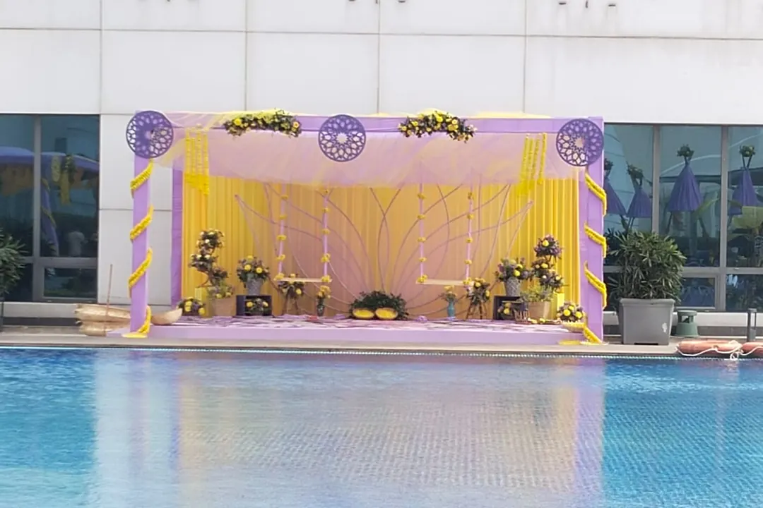 Haldi stage in lilac and marigold beside a rooftop pool