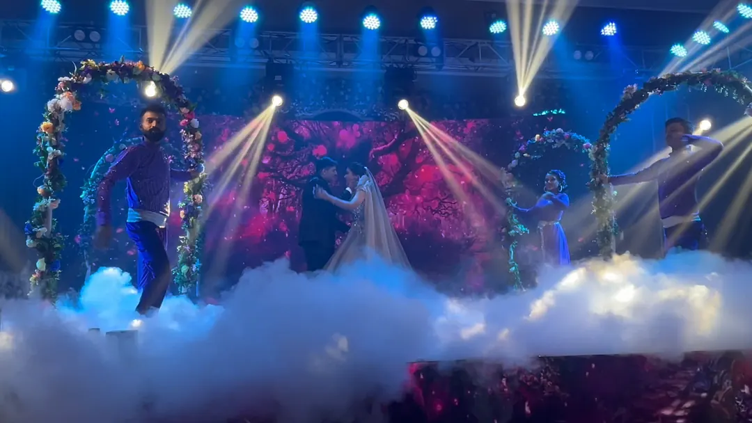 Moving-head beams and low fog across a wedding stage during a performance