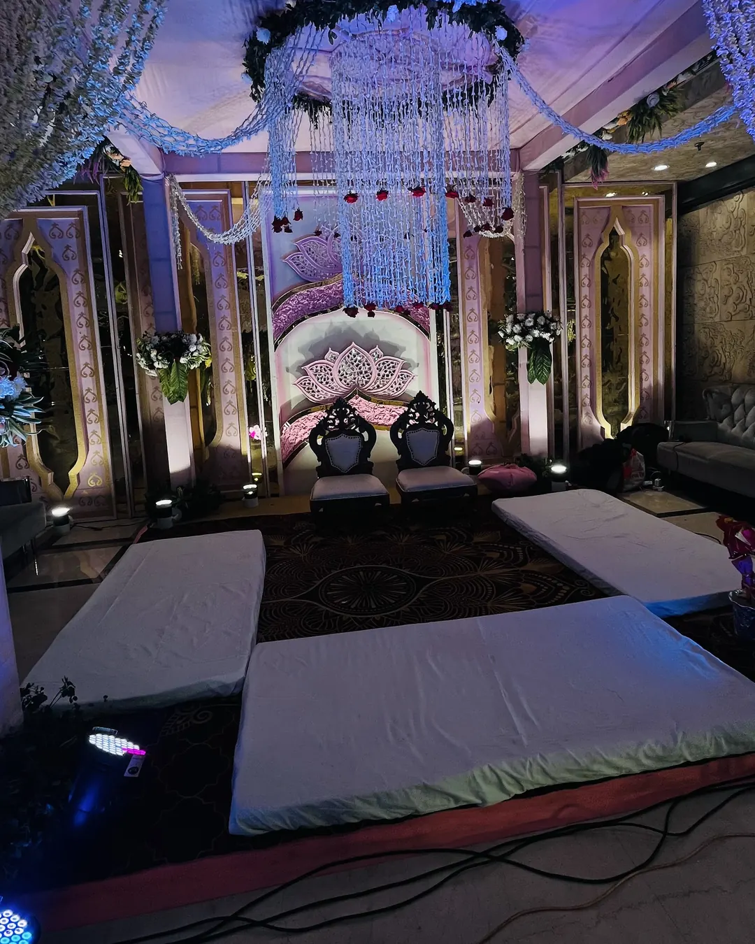 Wedding stage under a floral chandelier, with mirrored panels and a white aisle